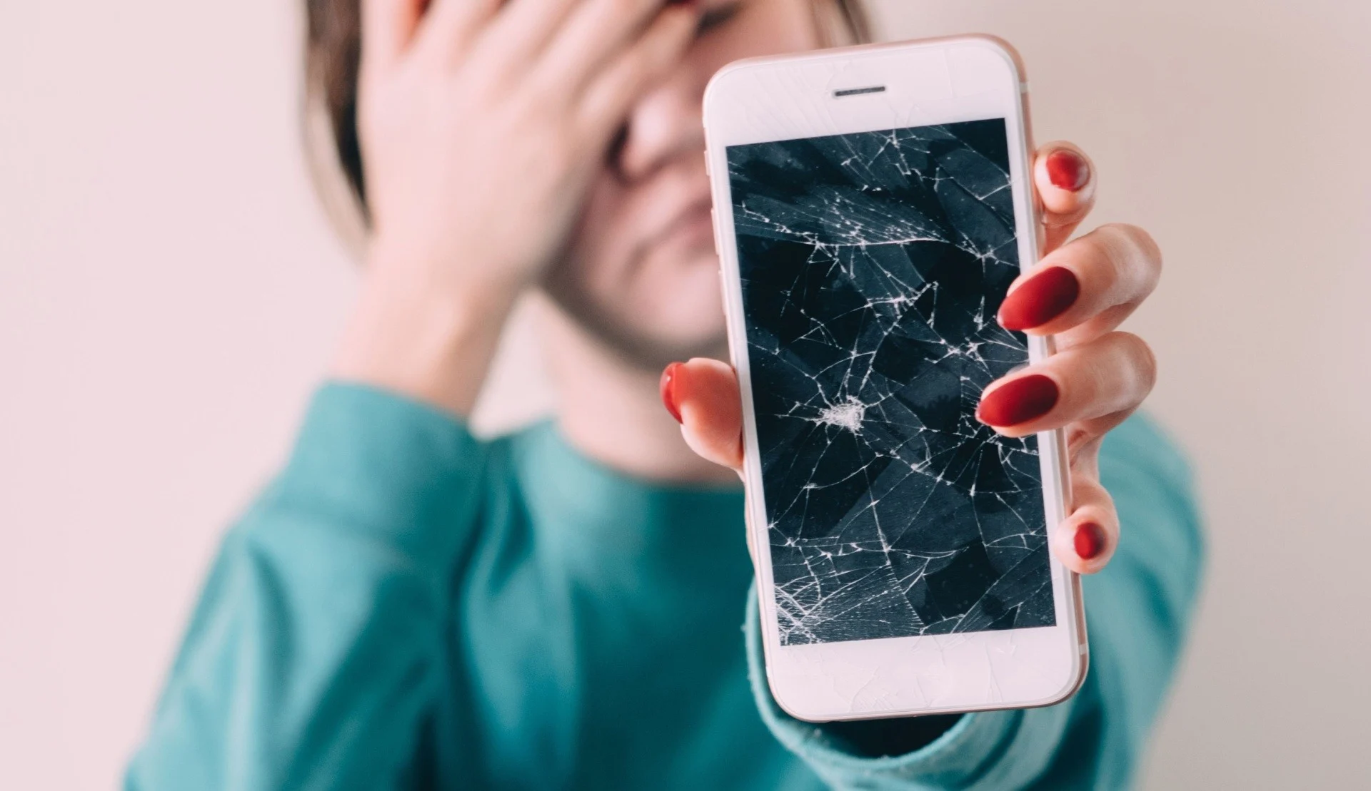 Cracked iPhone screen held up for inspection