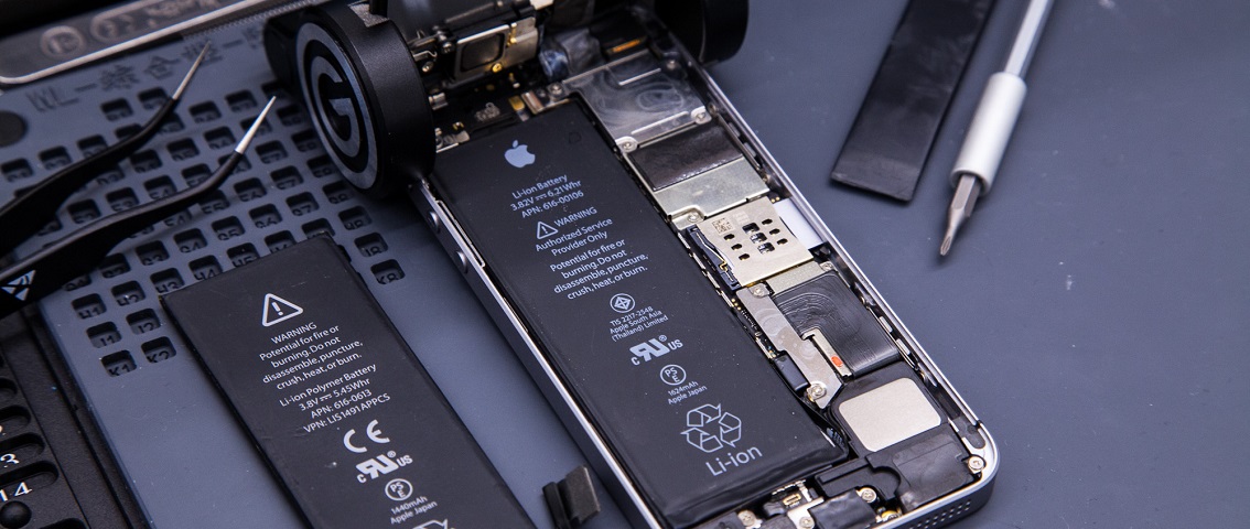Opened iPhone with a replacement battery beside it